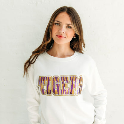 Woman wearing a white sweatshirt with 'HIGHER' printed on it against a plain background
