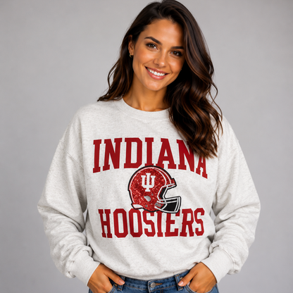 Model wearing the Indiana Hoosiers Football Slouchy Drop Shoulder Crewneck in oatmeal heather, featuring red Indiana Hoosiers lettering and a crimson sequin football helmet graphic.