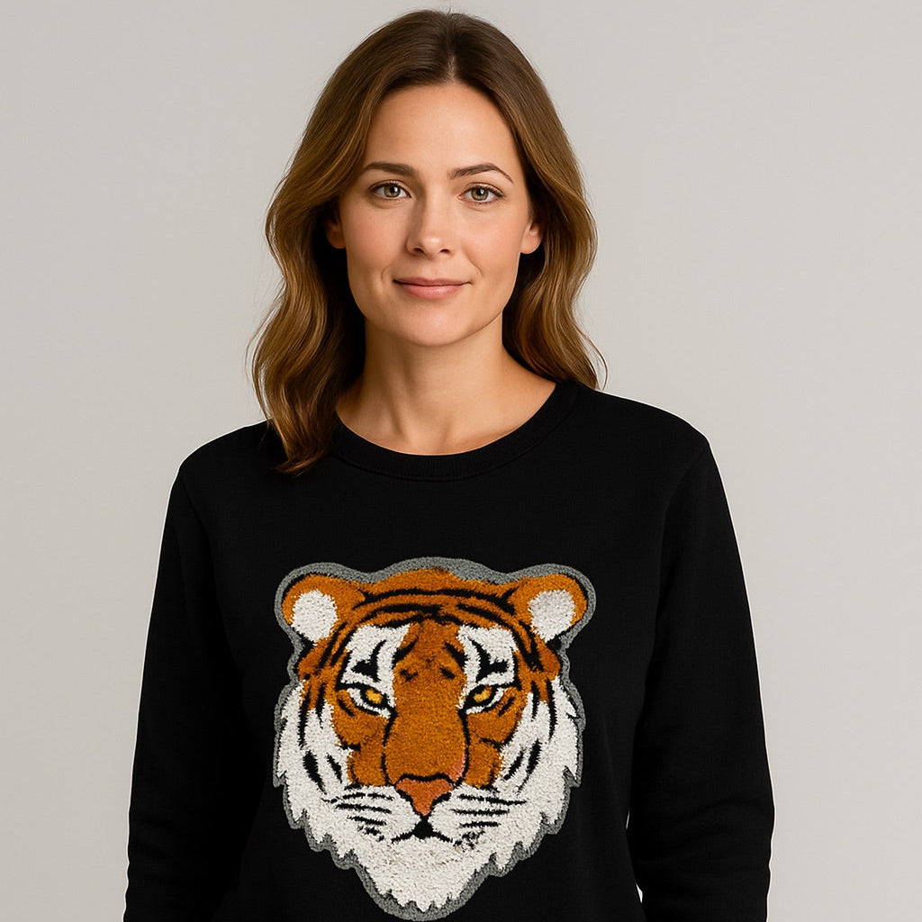 Woman wearing a black sweater with a tiger design on a plain background