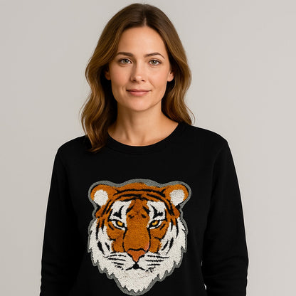 Woman wearing a black sweater with a tiger design on a plain background