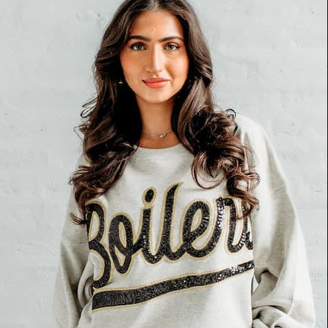 Front view of a model wearing the Purdue Boilers Sequin Slouchy Crewneck with black sequin “Boilers” lettering, gold trim, and a relaxed drop-shoulder fit.